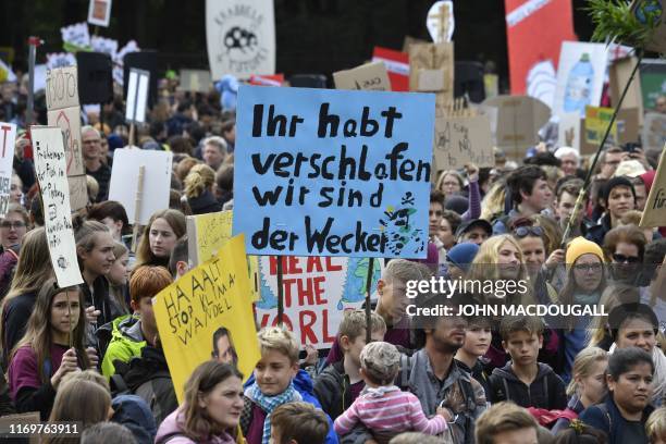 Protester holds a sign reading "you overslept, we are your alarm clock" during the "Fridays For Future" protest at the Brandenburg Gate in Berlin as...