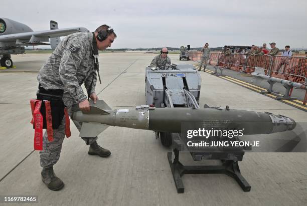 Airmen inspect a bomb to be loaded onto an A-10 Thunderbolt II close air support aircraft during a demonstration during "Air Power Day" preview at US...