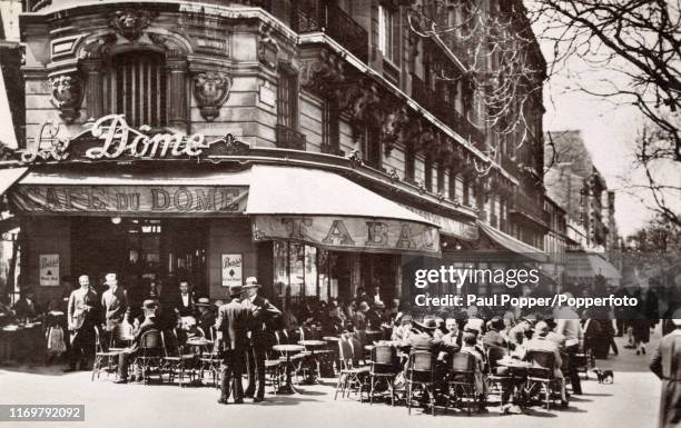 Vintage French postcard featuring a street scene around the Cafe du Dome in Montparnasse, Paris, circa 1925.
