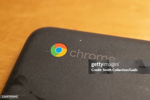 Close-up of logo for Google Chrome on the corner of a compact Google Chromebook laptop on a light wooden desk surface, San Ramon, California, August...