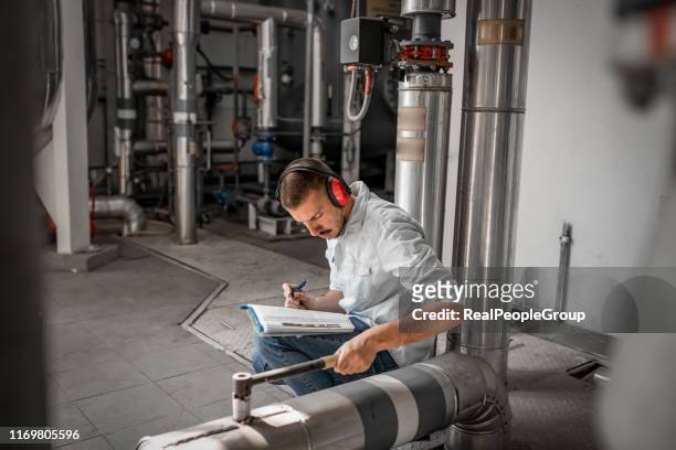young technician is inspecting heating system in boiler room - electric heater stock pictures, royalty-free photos & images