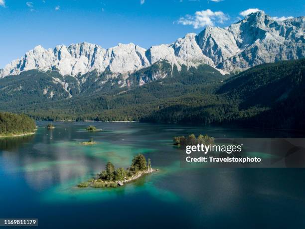 tiny islands in a clear blue water lake against blue sky and mountains - bavarian alps stock-fotos und bilder