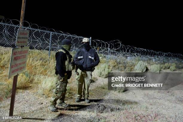 Law enforcement officers stand guard at a fence in an area attendees gathered to "storm" Area 51 at an entrance near Rachel, Nevada on September 20,...