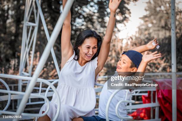 verticale de mère heureuse avec le fils au stationnement d'amusement - famille montagnes russes photos et images de collection