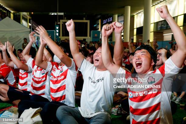 Fans react as the Japanese team scores a try while they watch the Japan 2019 Rugby World Cup Pool A match between Japan and Russia, on a big screen...