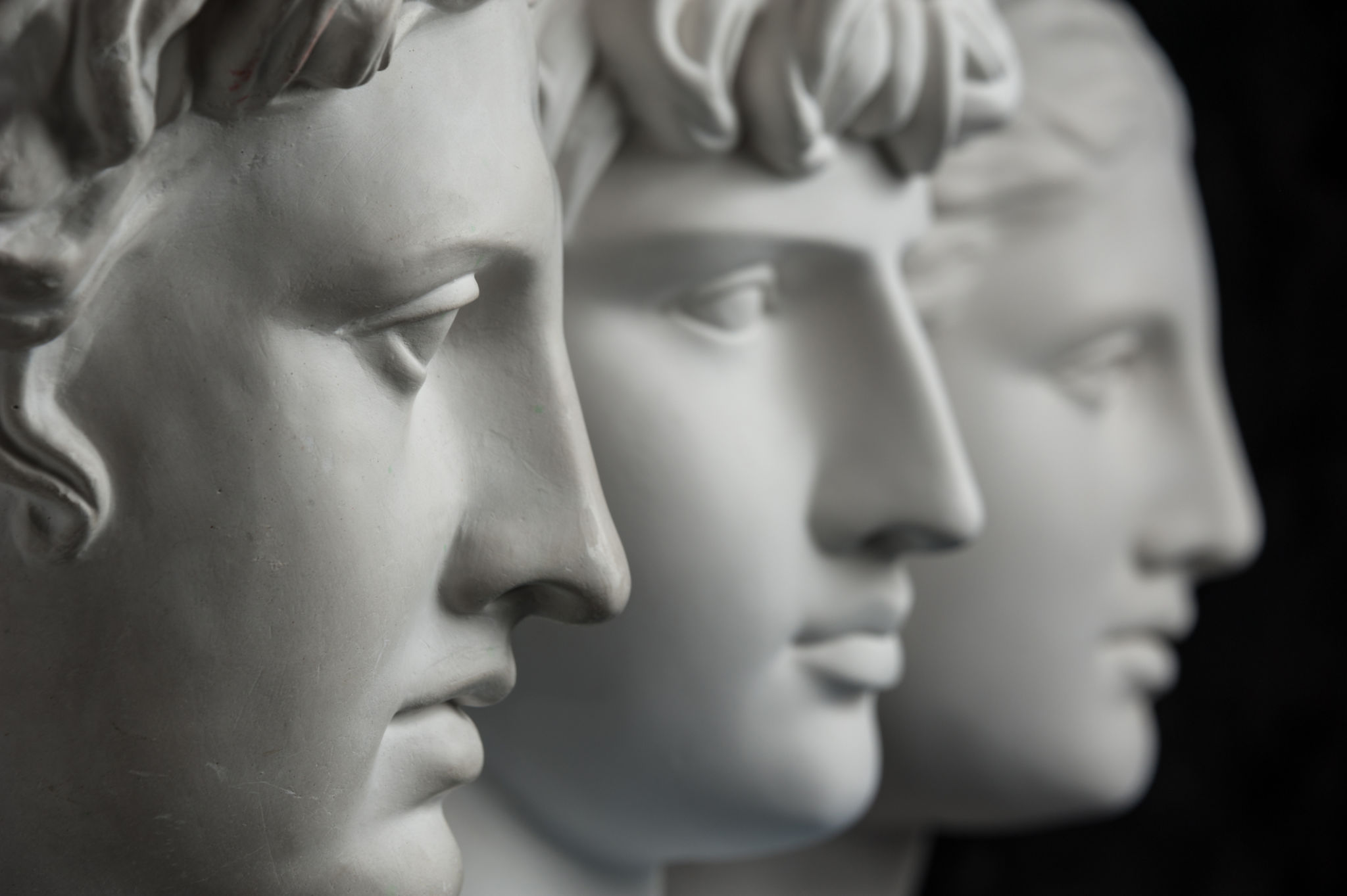 Gypsum copy of ancient statue Apollo, Antinous and Venus head on dark textured background. Plaster sculpture face. Gypsum copy of ancient statue Apollo, Antinous and Venus head on dark textured background. Plaster sculpture face.