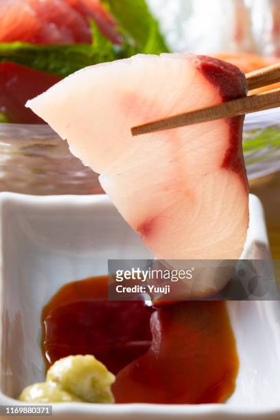japanese sashimi. grab the yellowtail fillet with chopsticks and add soy sauce. - japanese amberjack stock pictures, royalty-free photos & images