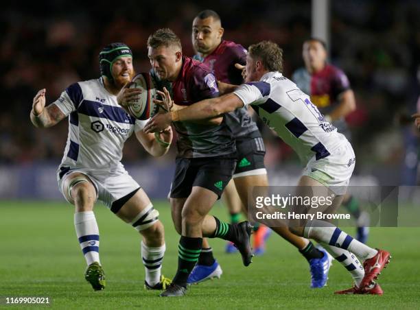 Will Evans of Harlequins is tackled by Jake Heenan and Tiff Eden of Bristol Bears during the Premiership Rugby Cup First Round match between...