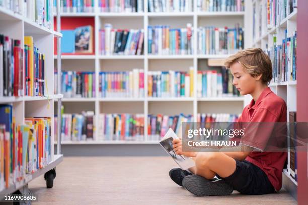 volledige lengte van de jongen lezen boek in de bibliotheek - 10 11 jaar stockfoto's en -beelden