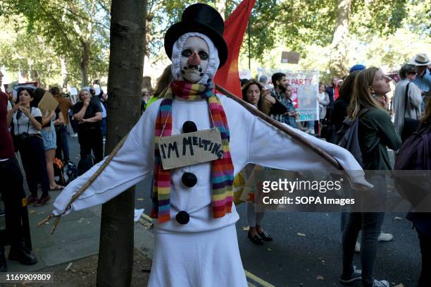 Protester seen wearing a snow man costume with a placard that says I'm melting during the demonstration. Adult and youth walking out of work and...