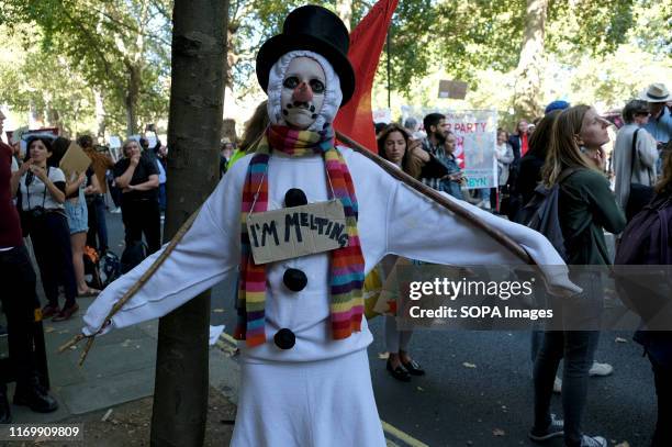 Protester seen wearing a snow man costume with a placard that says I'm melting during the demonstration. Adult and youth walking out of work and...