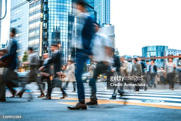 blurred group of business people commuting on the streets of japan - road intersection stock pictures, royalty-free photos & images