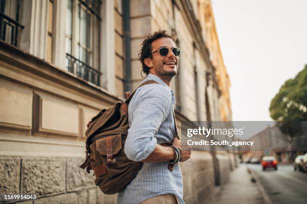 charming man with backpack in city - man backpack stock pictures, royalty-free photos & images