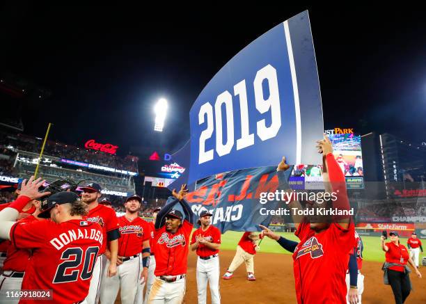 Ozzie Albies of the Atlanta Braves and Ronald Acuna Jr. #13 hold up a 2019 banner at the conclusion of an MLB game against the San Francisco Giants...