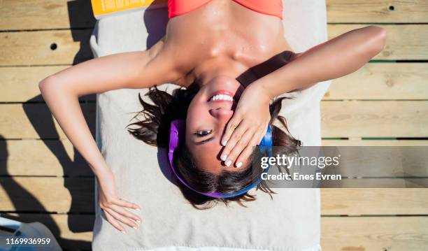 vrouw zonnen liggen en luisteren naar muziek door de zee - zonnebank stockfoto's en -beelden