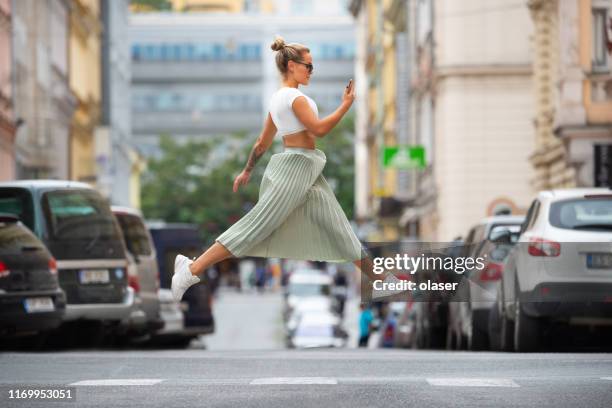 donna bionda cool attraversando la strada, saltando, in bilico, controllando il telefono - blonde woman selfie foto e immagini stock
