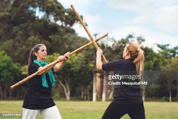frauen trainieren kung fu mit bambusstab - sparring training stock-fotos und bilder