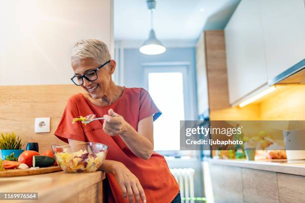 mature woman having salad  for lunch - mature women eating stock pictures, royalty-free photos & images