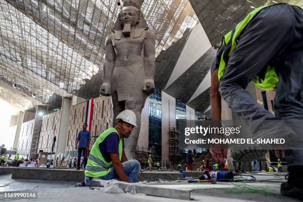 Egyptian workers continue construction work near the colossus of ancient Egyptian Pharaoh Ramses II, at its permanent display spot in the newly-built...