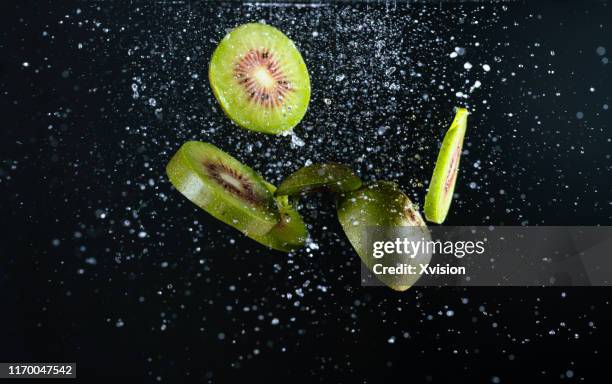 kiwi fruit dancing in mid air with water captured with high speed sync. - flying kiwi stock pictures, royalty-free photos & images