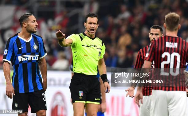 Italian referee Daniele Doveri reacts next to Inter Milan's Italian defender Danilo D'Ambrosio and AC Milan's Spanish forward Suso during the Italian...