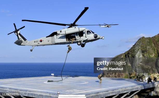 In this photo provided by South Korean Navy, South Korean Navy's special forces participate during the drill on the islets called Dokdo in Korean and...