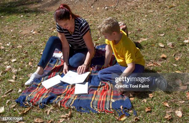 family time as an aunt spends time with her nephew in the sun reading books - happy sprong two persons sun stock-fotos und bilder