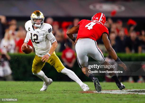 Notre Dame Fighting Irish quarterback Ian Book scrambles on fourth down as he is pressured by Georgia Bulldogs linebacker Nolan Smith during the...