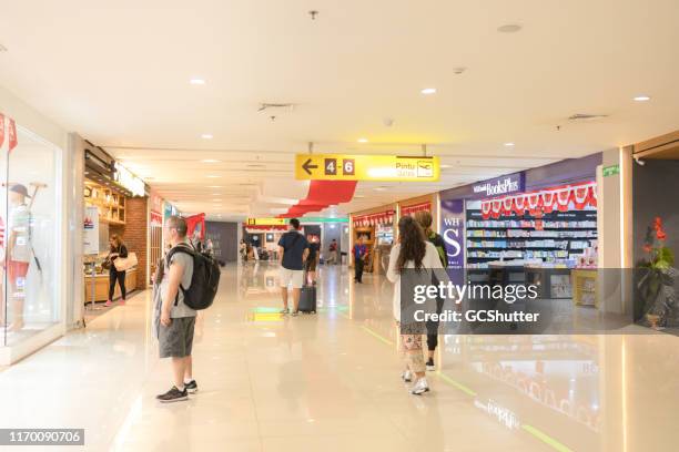 tourist exploring souvenir store at  ngurah rai international airport, bali indonesia - bali airport stock pictures, royalty-free photos & images