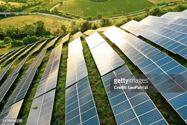 champs de panneaux solaires sur les collines vertes - land feature stock photos et images de collection