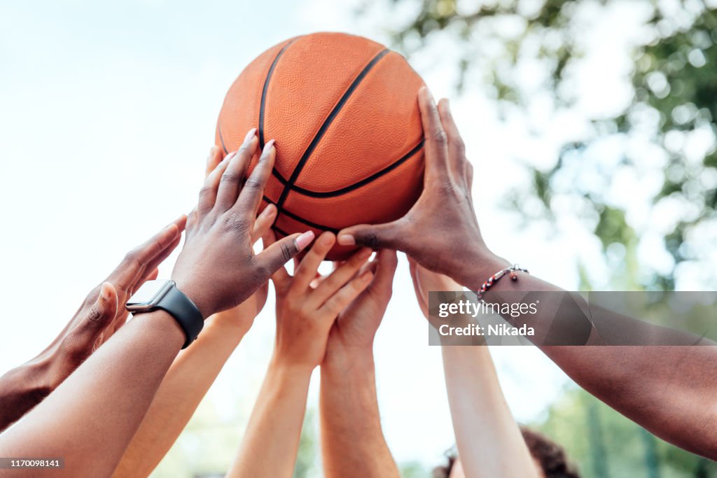 Multiethnische Freunde, die Basketball halten