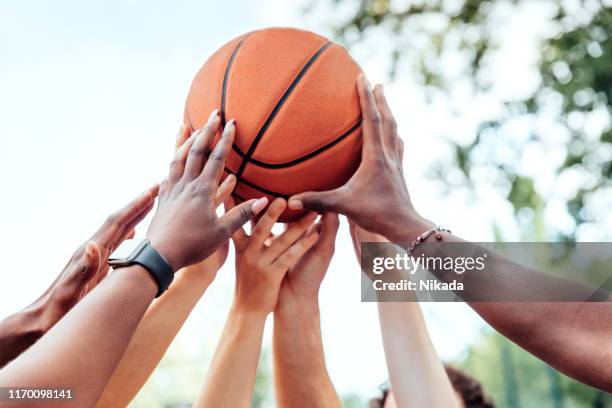 multi-ethnic friends holding basketball - basketball teamwork stock pictures, royalty-free photos & images