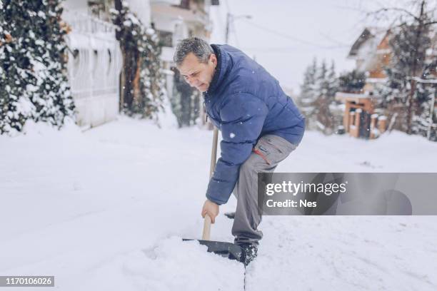 man cleaning snow on the street - older man snow shovel stock pictures, royalty-free photos & images