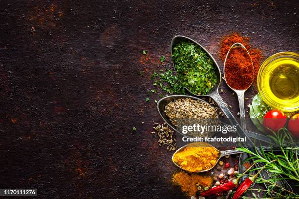 fondos de cocina y condimento: especias y hierbas en cucharas vintage disparadas desde arriba en una mesa marrón rústica - orégano fotografías e imágenes de stock