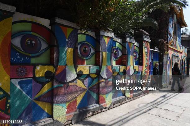 People walk past street art in Bellavista neighbourhood. Bellavista is located between the north bank of the Mapocho River and San Cristóbal Hill, it...