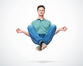 Happy man in casual clothes closing his eyes meditating levitating in the air. Comprehended relaxation