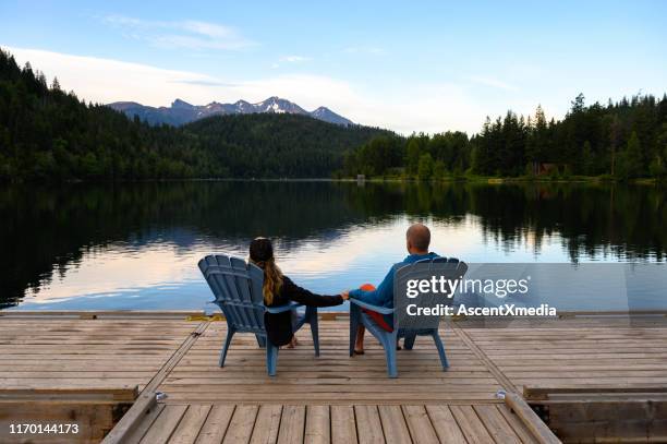 couples détendant sur la jetée au-dessus du lac pendant des vacances - chaise adirondack photos et images de collection