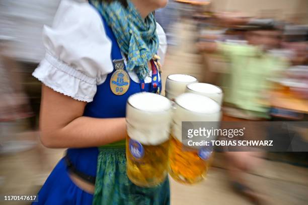 Waitress carries beer glasses in a beer tent at the Oktoberfest beer festival in Munich, southern Germany, on September 22, 2019. The world's biggest...