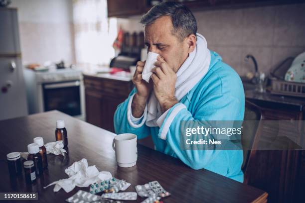 wide angle perspective of handsome senior man at home feeling unwell and coughing as symptom for cold or bronchitis. - angular face stock pictures, royalty-free photos & images