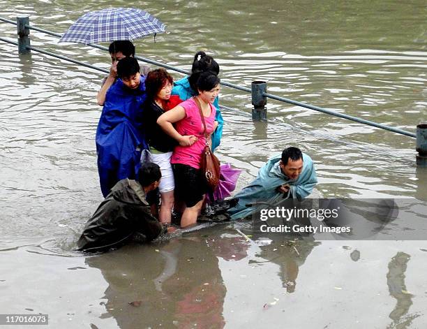 Pedestrians wade in a flooded street after heavy rainfall on June 18, 2011 in Wuhan, Hubei Province of China. A heavy rainstorm hit Wuhan on...