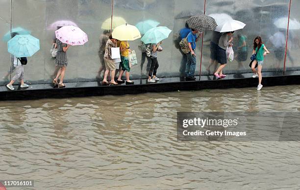 Pedestrians walk on the isolation belt after heavy rainfall on June 18, 2011 in Wuhan, Hubei Province of China. A heavy rainstorm hit Wuhan on...