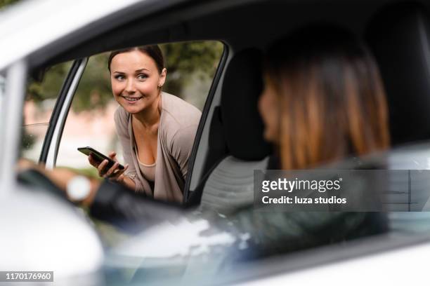woman ordering a taxi with her smart phone on a rainy day - entering stock pictures, royalty-free photos & images