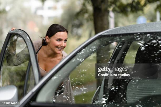 mujer pidiendo un taxi con su teléfono inteligente en un día lluvioso - entrando fotografías e imágenes de stock