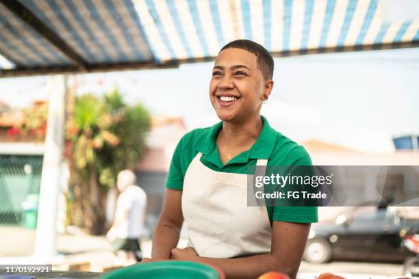junge frau verkauft obst an einen kunden auf einem straßenmarkt - straßenverkäufer stock-fotos und bilder