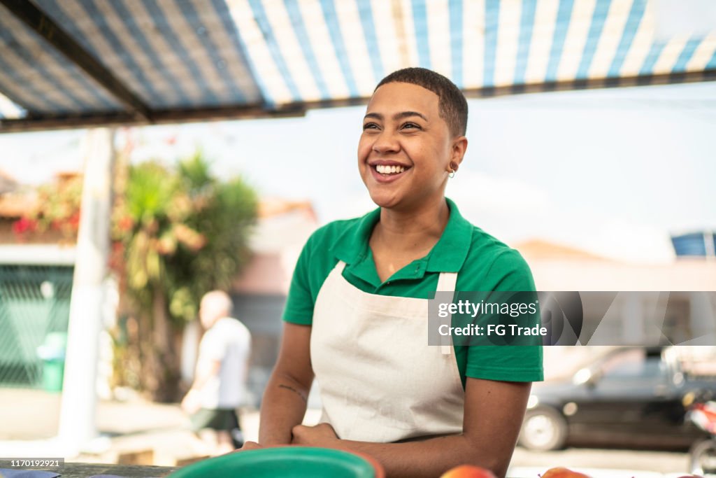 Mujer joven vendiendo frutas a un cliente en un mercado callejero