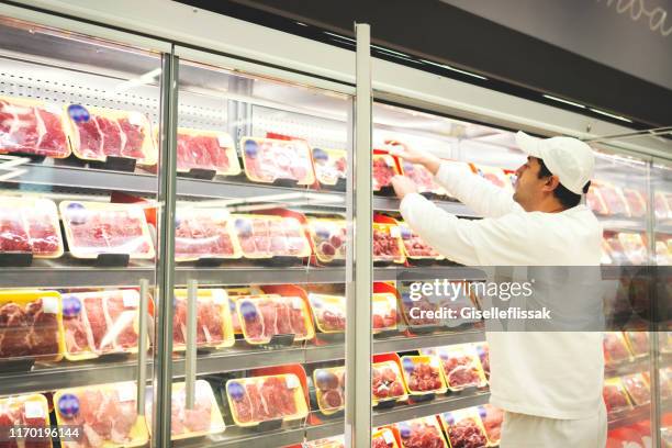 worker in a supermarket handling meat - meat packaging imagens e fotografias de stock