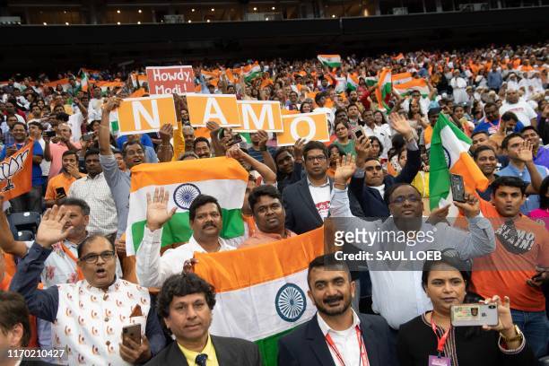 People cheer and hold the flag of India as US President Donald Trump and Indian Prime Minister Narendra Modi attend "Howdy, Modi!" at NRG Stadium in...