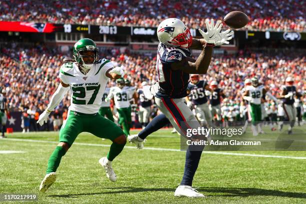 Josh Gordon of the New England Patriots bobbles a throw from Tom Brady of the New England Patriots while under pressure from Darryl Roberts of the...