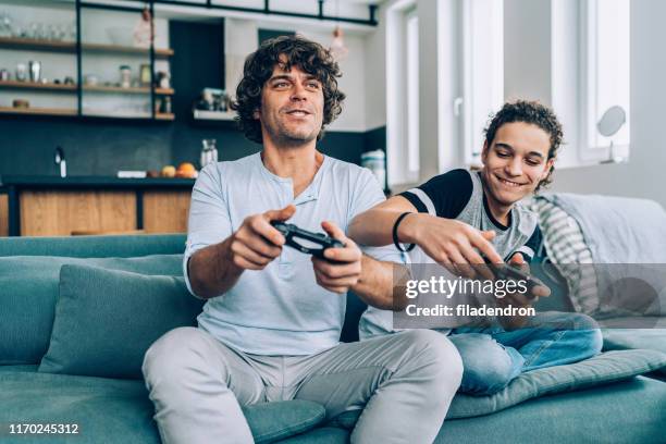 father and son playing video game - gaming imagens e fotografias de stock