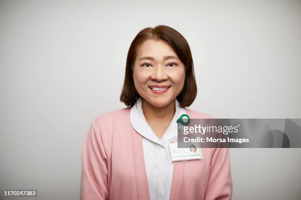 portrait of smiling female nurse in uniform - nurse and portrait and white background and smiling and female and looking at camera stock-fotos und bilder